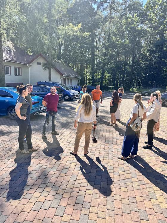 Uczestnicy na dziedzińcu ośrodka wśród sosen